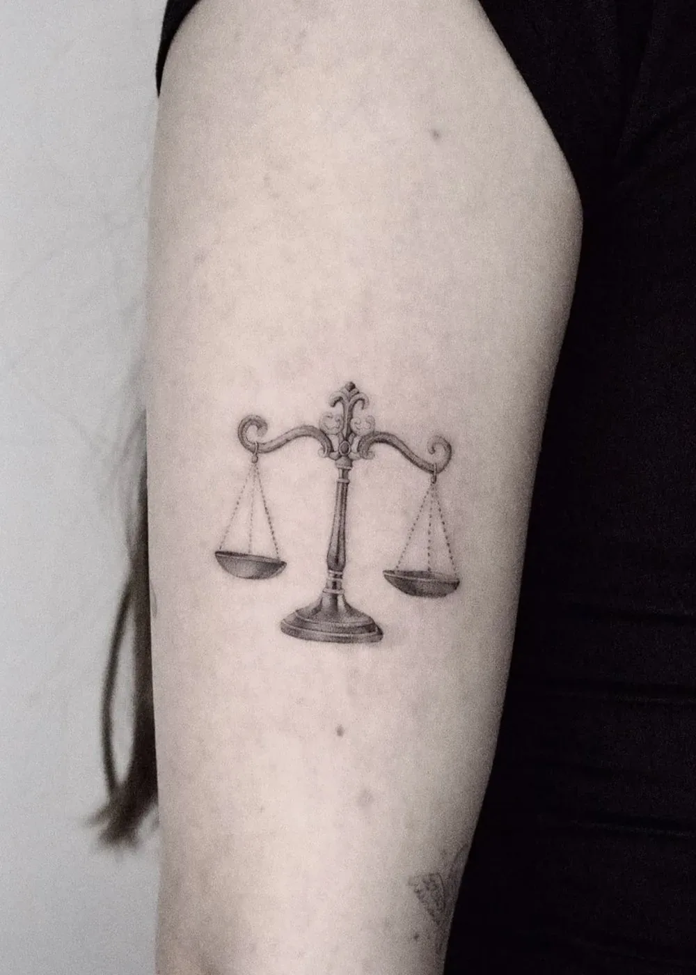 Eine Waage im Gleichgewicht, Tattoo am Oberarm von Barni