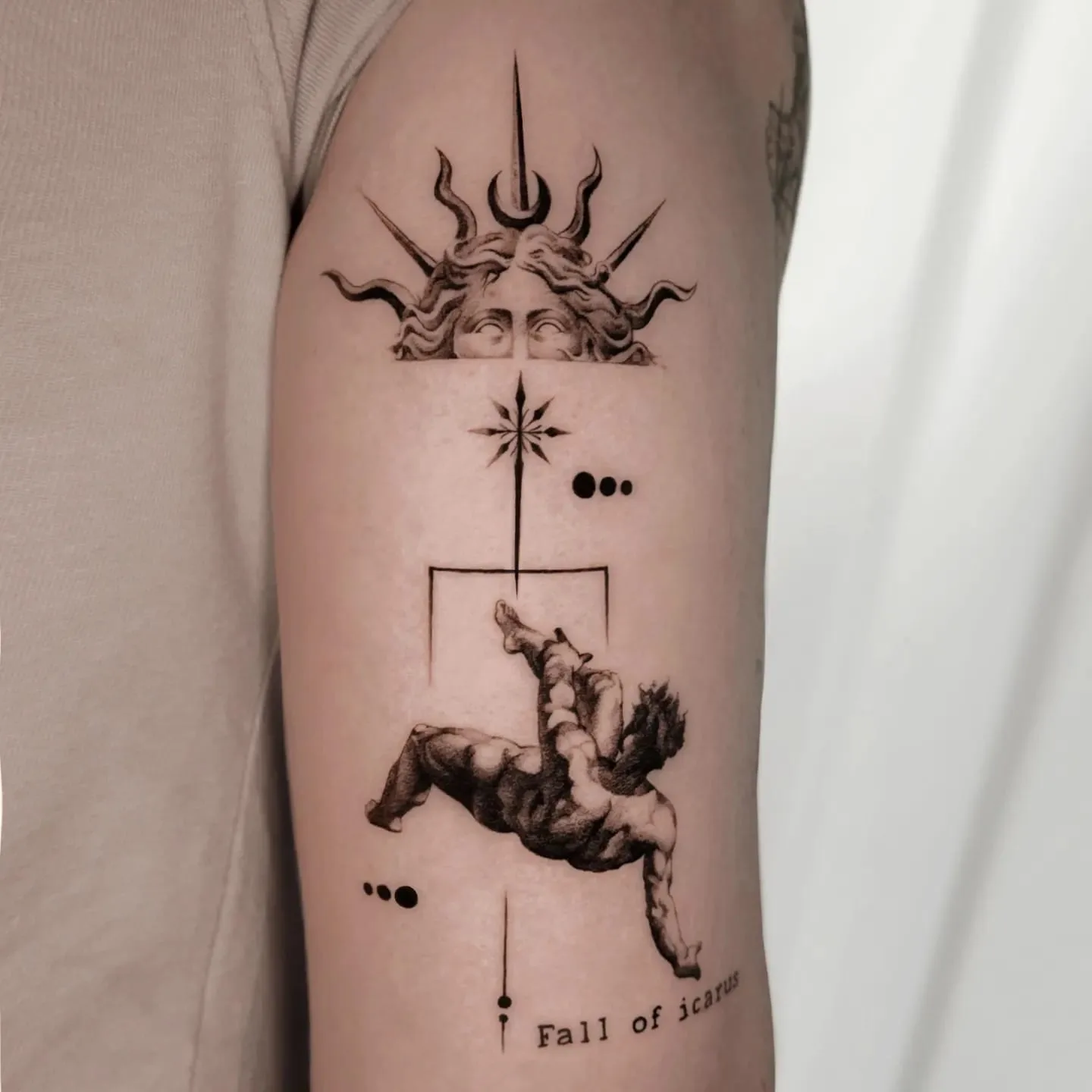 Oben Medusa mit Strahlen, darunter ein Stern und der fallende Ikarus. Fine-Line-Tattoo von Inna auf dem Oberarm.