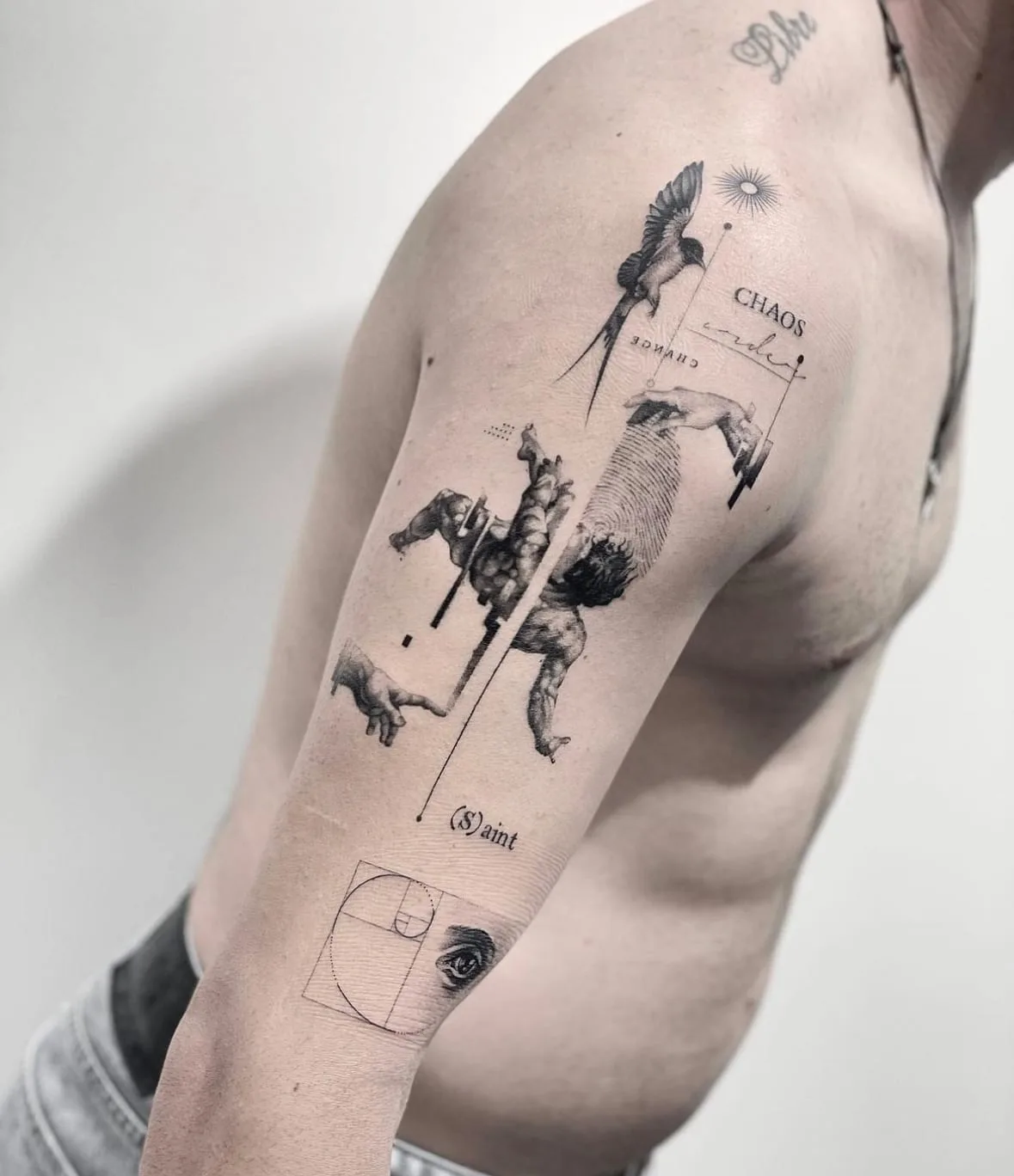 Schwalbe, Hände, eine stürzende Figur und die Worte Chaos, Order und (S)aint, dazu eine goldene Spirale mit Auge. Black-and-Grey-Tattoo von Sloan auf dem Oberarm.