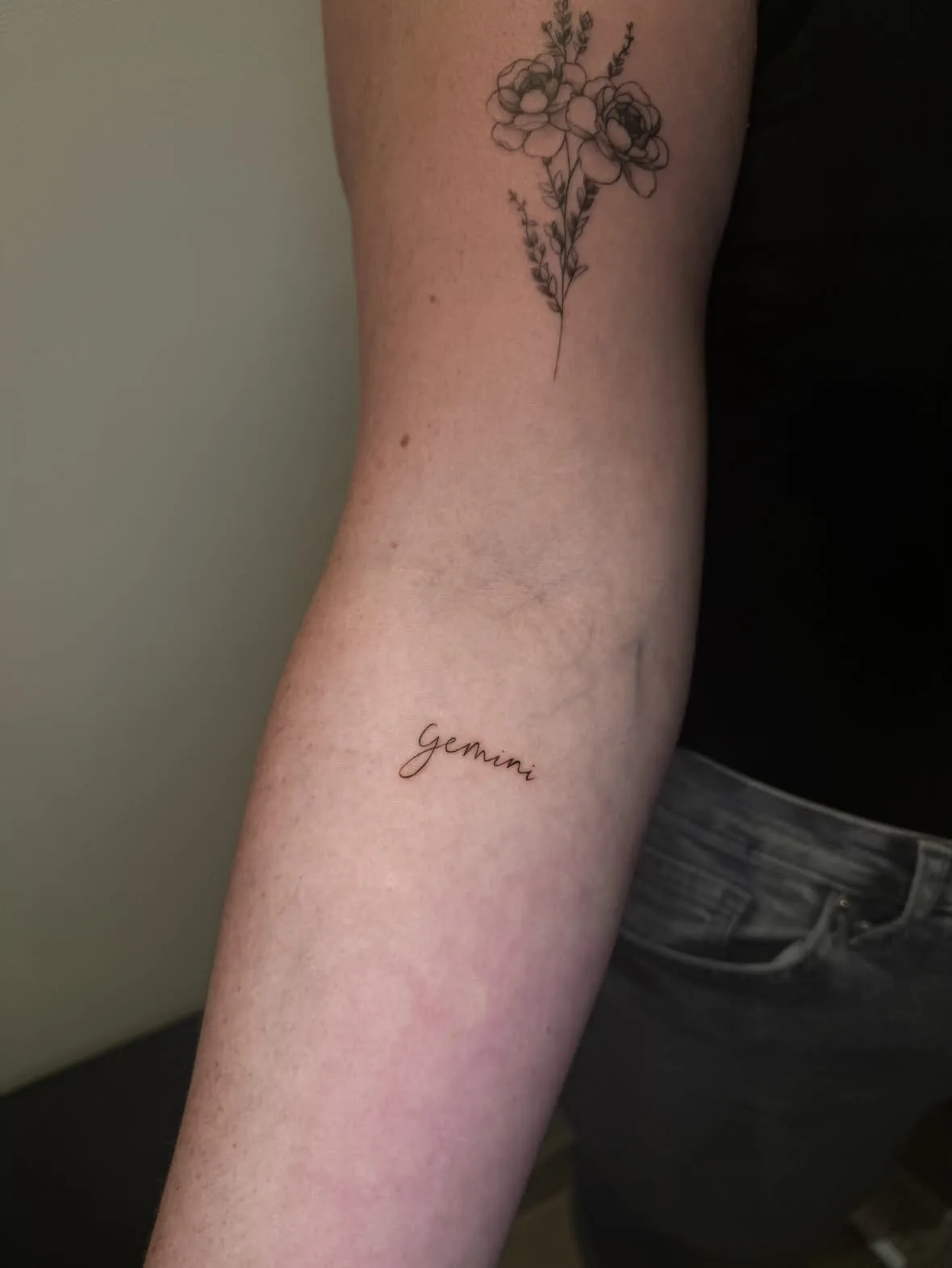 Der Schriftzug Gemini in feiner Handschrift. Fine-Line-Tattoo von Inna auf dem Unterarm.