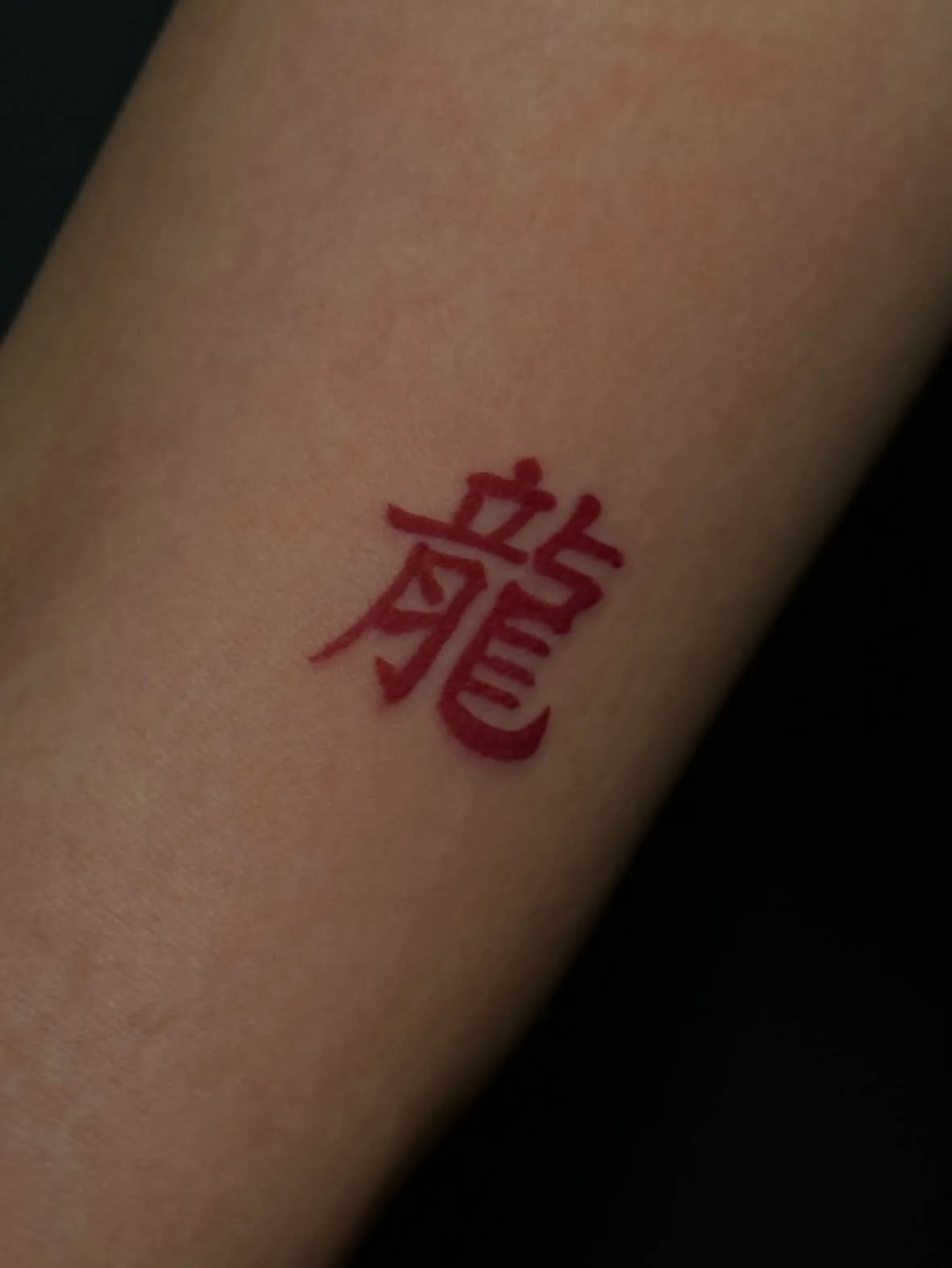 Schriftzeichen für Drache in Rot. Tattoo in Farbe von Inna auf dem Unterarm.