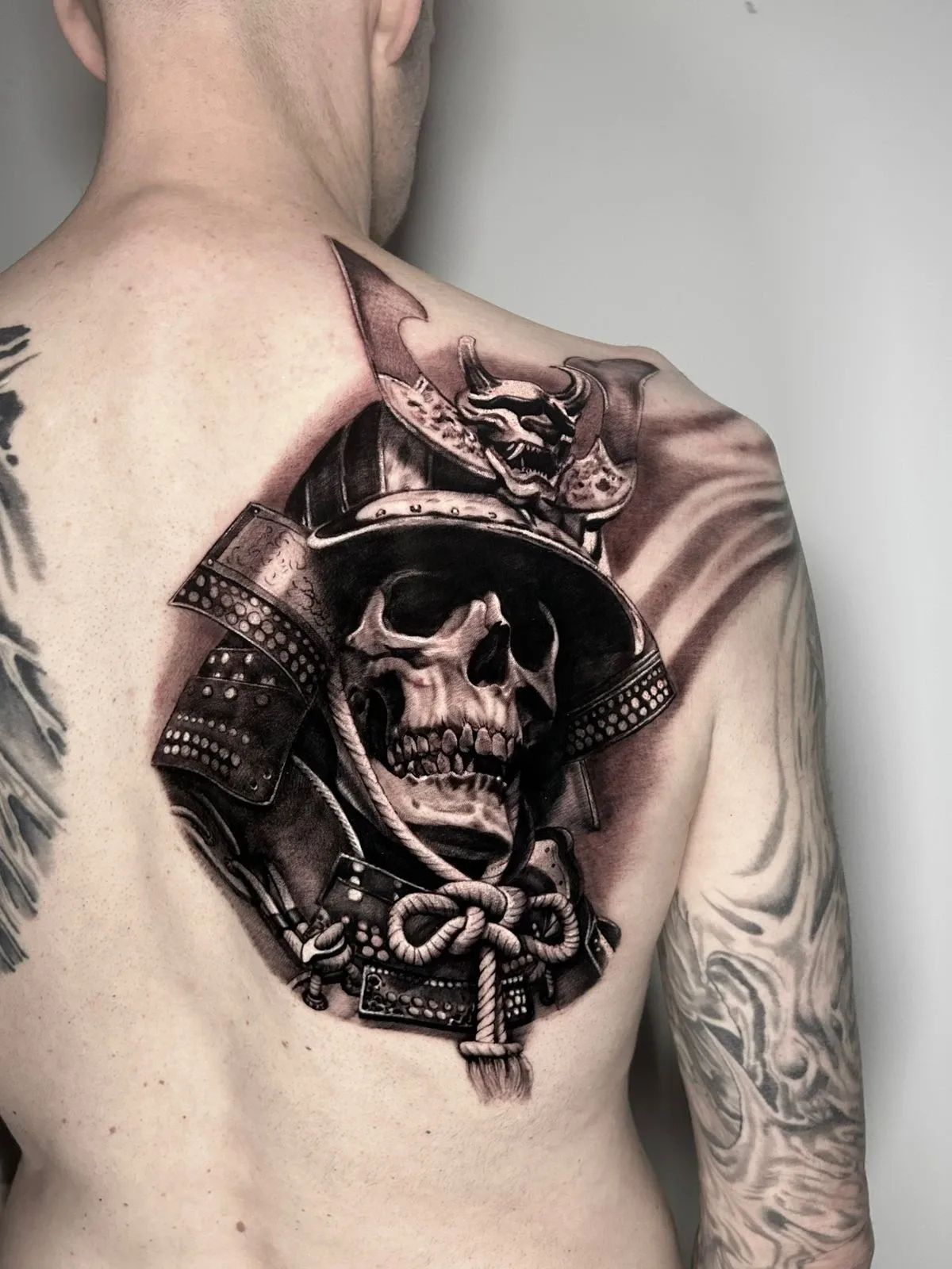 Samurai-Schädel mit detailreichem Helm als Black-and-Grey-Tattoo von Ruby auf dem Schulterblatt