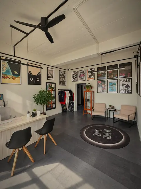 Besprechungsraum mit schwarzen Stühlen, rundem Teppich mit Logo und Postern an der Wand.